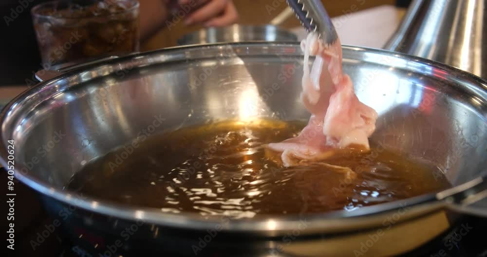 Male chef smears fried meat with soy sauce in pan at kitchen interior irrl. Closeup view of cook is preparing tasty pieces on sticks on hot surface at stove. Professional has working day in asian Male chef smears fried meat with soy sauce in pan at kitchen interior irrl. Closeup view of cook is preparing tasty pieces on sticks on hot surface at stove. Professional has working day in asian