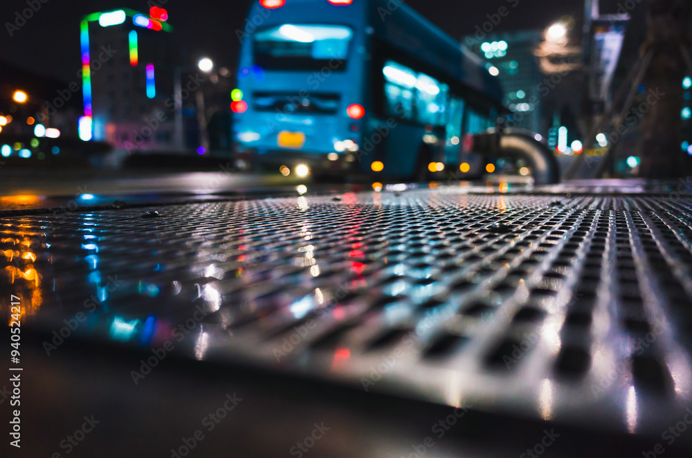 Abstract dark night city photo with shiny wet street sewer grate on urban road Abstract dark night city photo with shiny wet street sewer grate on urban road