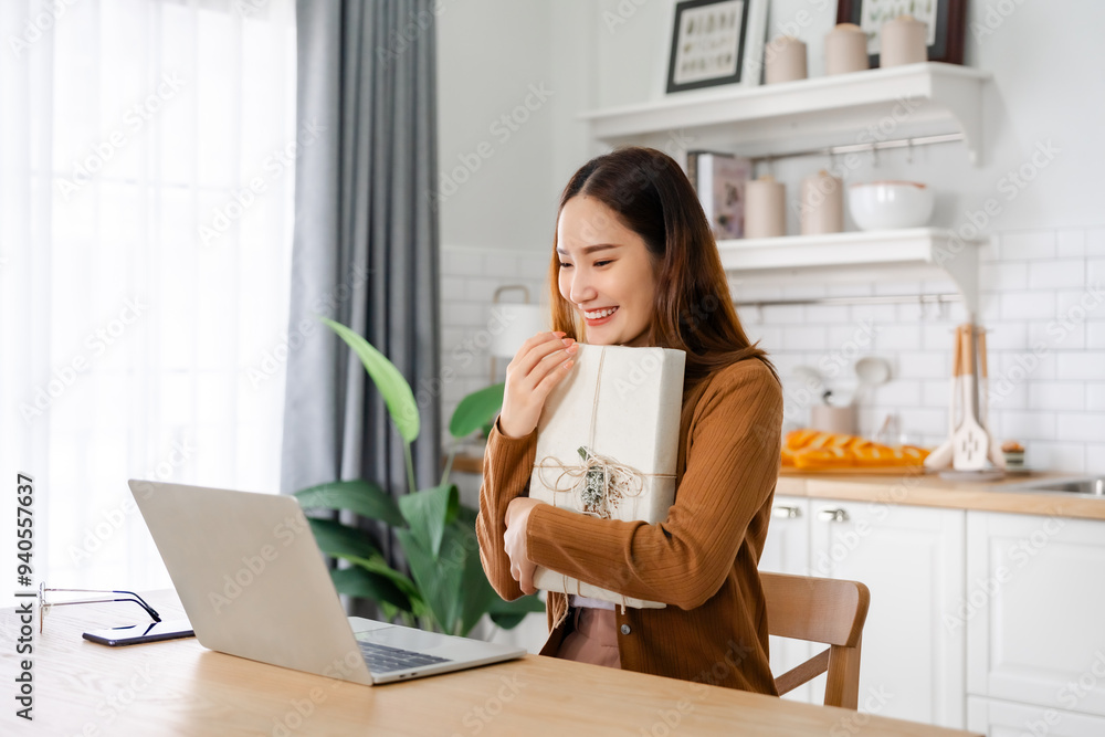 Young asian woman using computer laptop at home. Female showing gift box while on video conversation with friend. Happy birthday, Happy new year, Thanksgiving Young asian woman using computer laptop at home. Female showing gift box while on video conversation with friend. Happy birthday, Happy new year, Thanksgiving