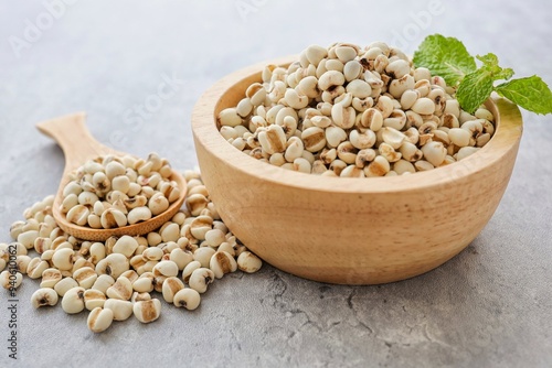 Job's tears  with wooden spoon in a wooden bowl on geay cement background photo