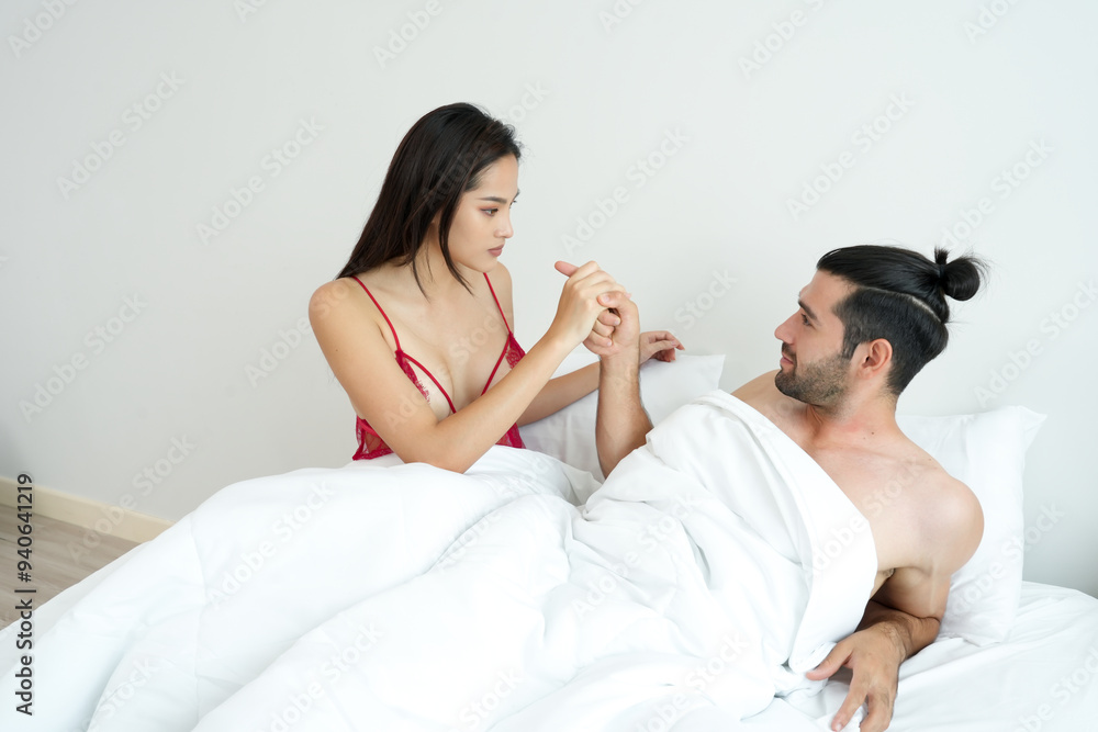 Couple is seated in bed, holding hands engaged in a serious and emotional conversation when boyfriend pointing finger and girlfriend angry reflecting a moment of intimacy and concern Couple is seated in bed, holding hands engaged in a serious and emotional conversation when boyfriend pointing finger and girlfriend angry reflecting a moment of intimacy and concern