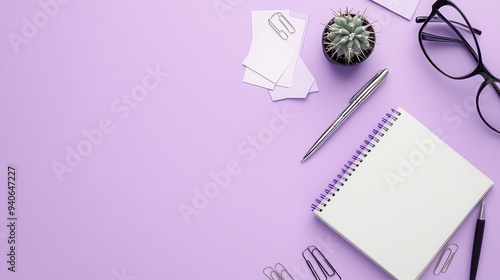 Top view of a workspace with a notebook, pen, glasses, and small plant on a lavender desk, ideal for creative projects and organization. photo