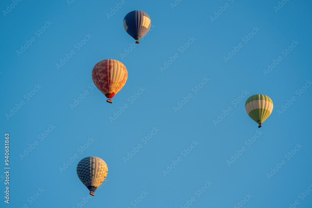 Fototapeta premium Hot air balloons in dark blue, red and yellow colors flying in a slightly cloudy blue sky