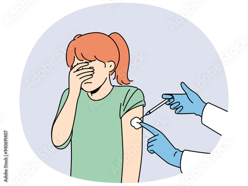 Crying little girl is afraid of injections and closes eyes during injection in shoulder and vaccination against measles or flu. Hands of doctor with syringe making injection to child
