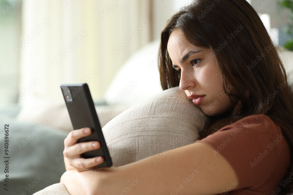 Sad woman hugging pillow checking phone Sad woman hugging pillow checking phone