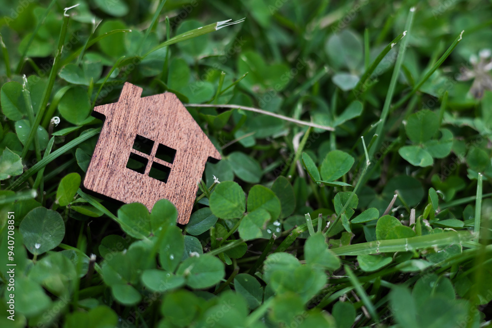 Little wood home model on green nature background. Eco friendly home concept.