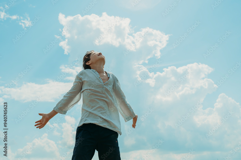 Carefree boy with arms outstretched standing under cloudy sky Carefree boy with arms outstretched standing under cloudy sky