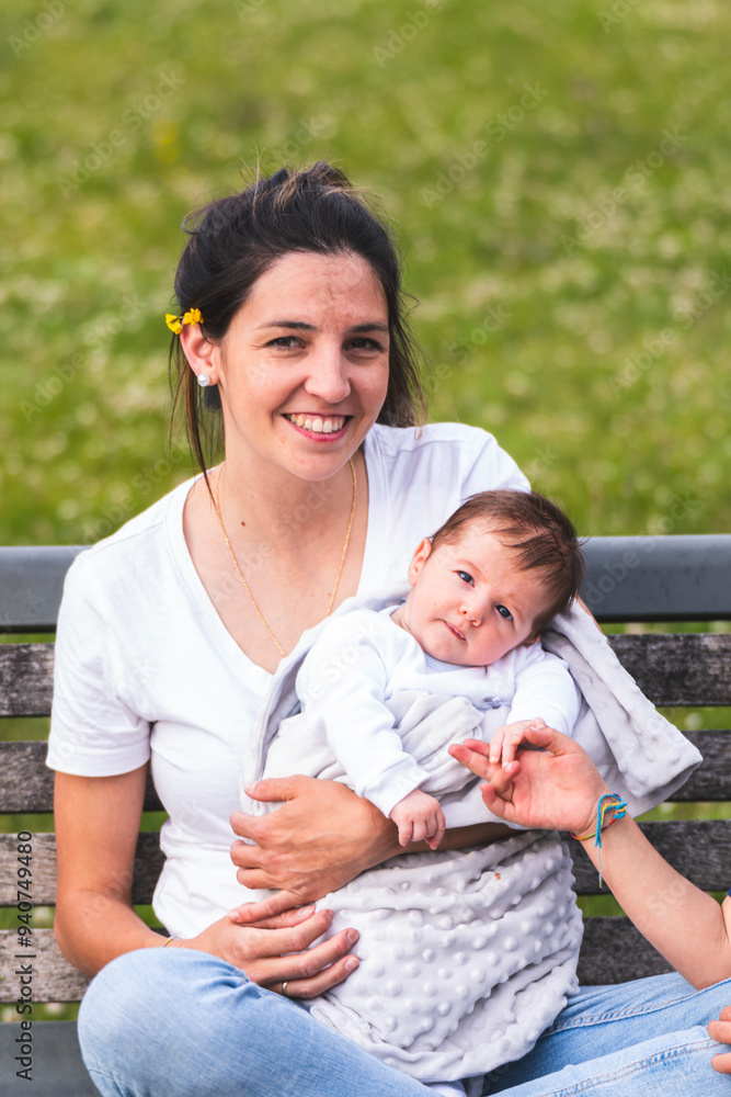 Smiling mother sitting with baby boy on bench at playground Smiling mother sitting with baby boy on bench at playground