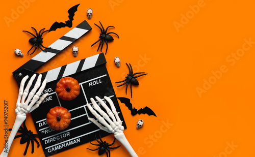 Halloween movies concept. Movie clapperboard with skeleton hands,funny halloween pumpkins and spiders with copy space for text. Halloween concept background