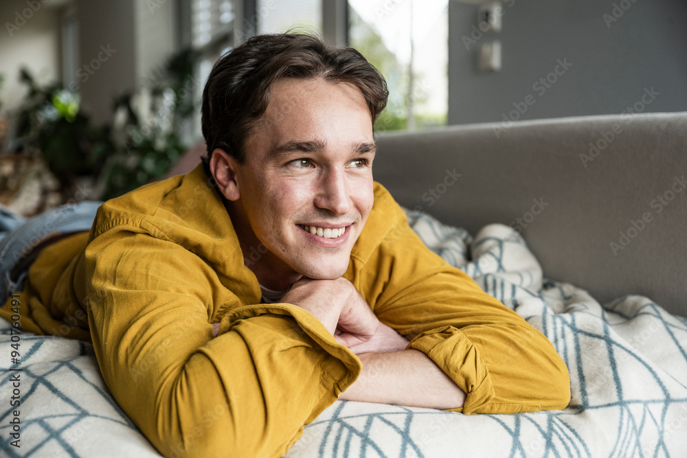 Smiling young man lying on sofa and day dreaming at home Smiling young man lying on sofa and day dreaming at home