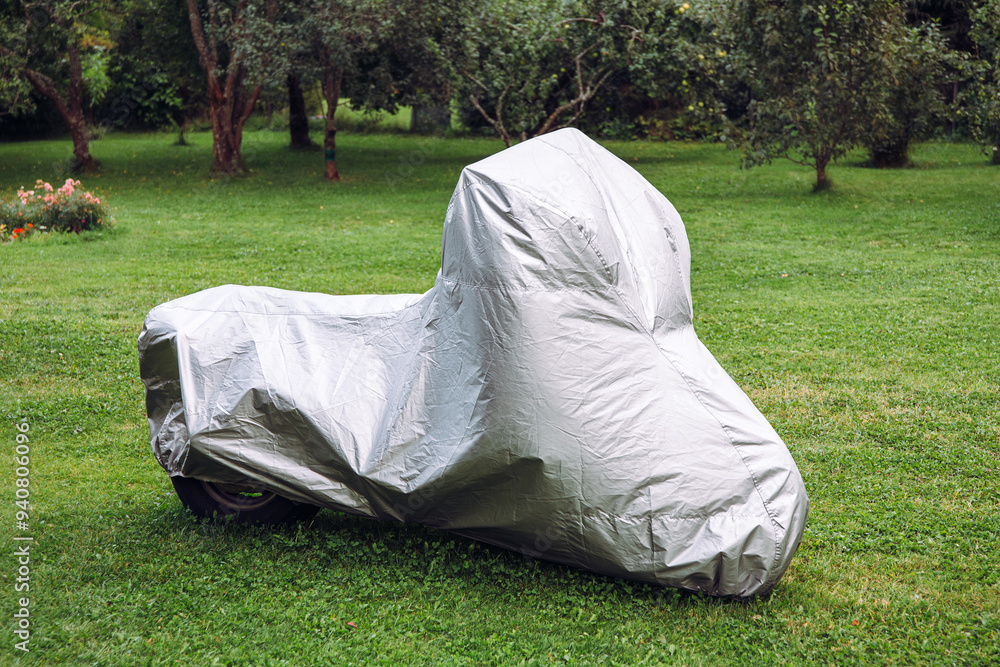 Motorcycle parked in home garden and is covered with gray color waterproof motorcycle cover. Motorcycle parked in home garden and is covered with gray color waterproof motorcycle cover.