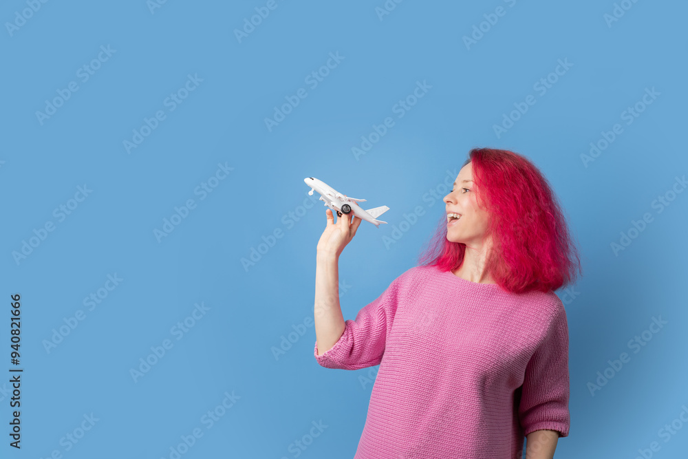 Summer travel, woman with pink hair with an airplane in hands on blue background, young person planning a vacation. Summer travel, woman with pink hair with an airplane in hands on blue background, young person planning a vacation.