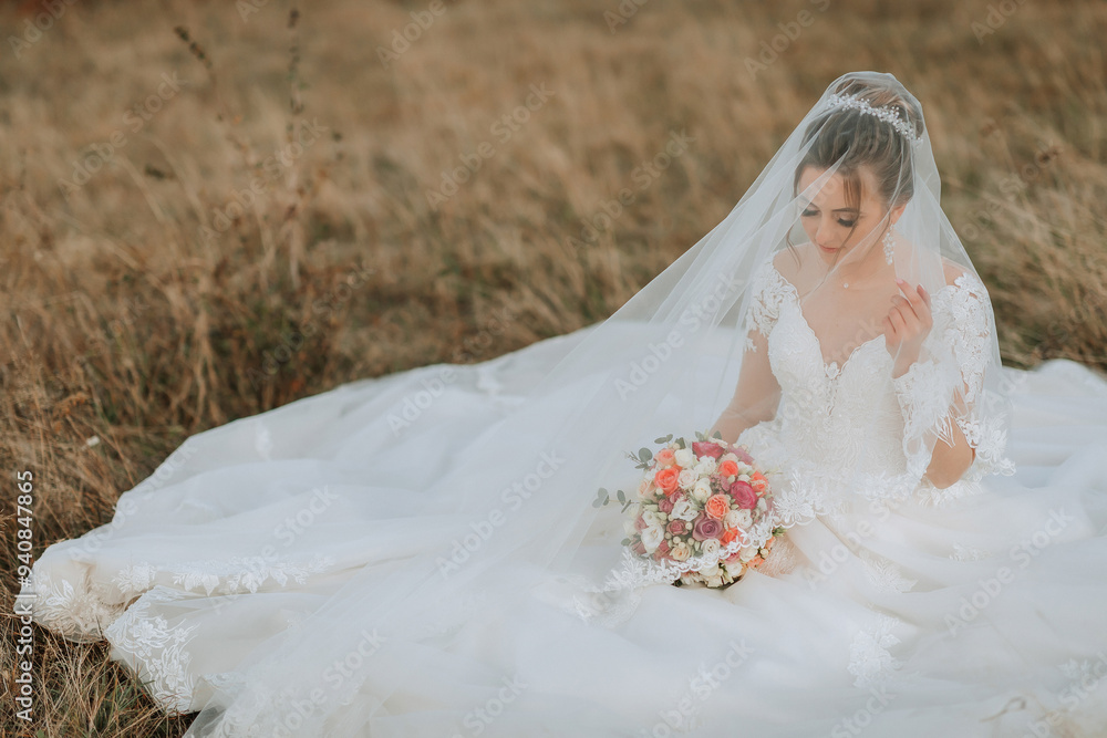 A bride is sitting in a field with a bouquet of flowers in her lap. She is wearing a veil and a white dress A bride is sitting in a field with a bouquet of flowers in her lap. She is wearing a veil and a white dress