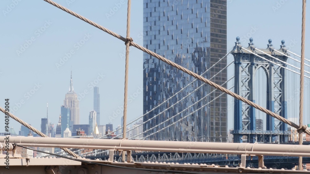 Obraz premium New York City Manhattan Bridge from Brooklyn Bridge view. Empire State building in Midtown. USA travel landmark, NYC skyline cityscape. Iconic architecture thru cables. Visit United States of America.