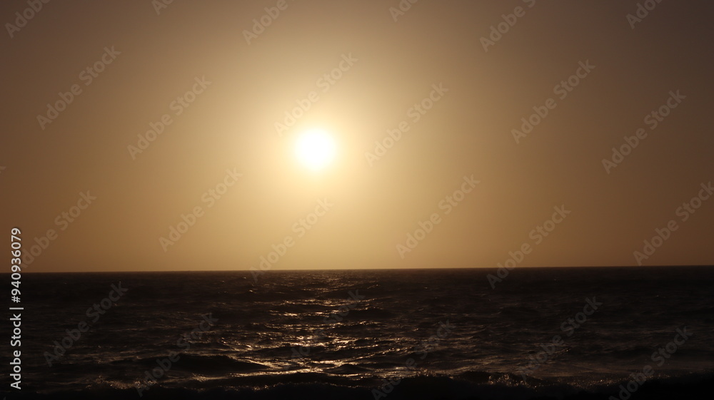 Fototapeta premium Seagulls Flocking on Rocky Shoreline at Sunset with Ocean Waves Crashing, Coastal Wildlife Birds in Flight, Group of Seagulls Gathering on Beach, Seascape at Dusk with Waves and Birds in Natural