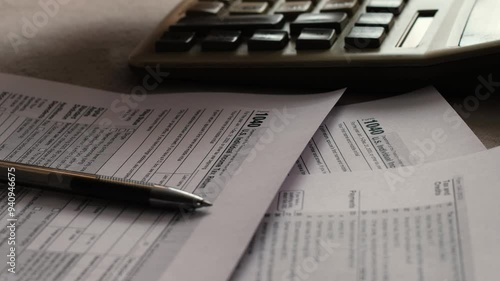 concept calculation and payment of taxes of a US citizen, tax form 1040 on the table, pen and hand counting on a push-button calculator, tax deductions filling out a declaration