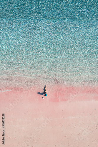 Top view of a girl sitting on the pink sand beach and blue sea in Komodo, Indonesia photo