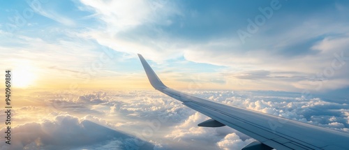  An airplane wing silhouette against the sky, adorned with clouds in the foreground and the sun setting in the distance