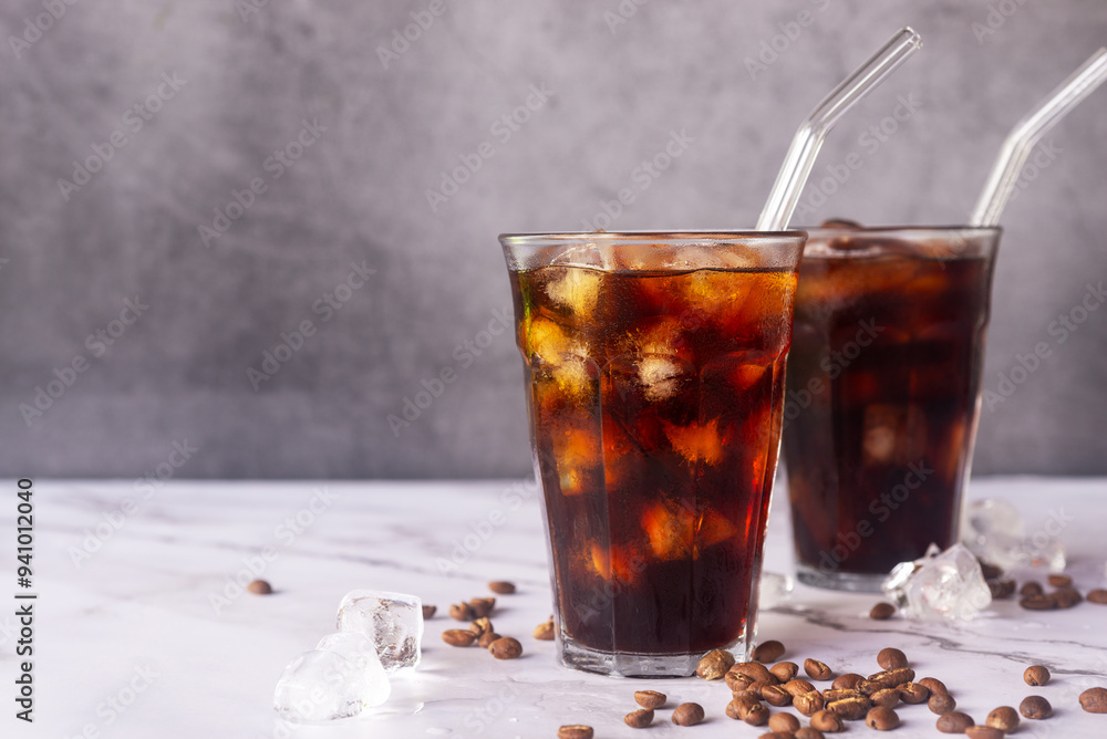iced homemade cold brew coffee with glass straw on white marble table. iced homemade cold brew coffee with glass straw on white marble table.