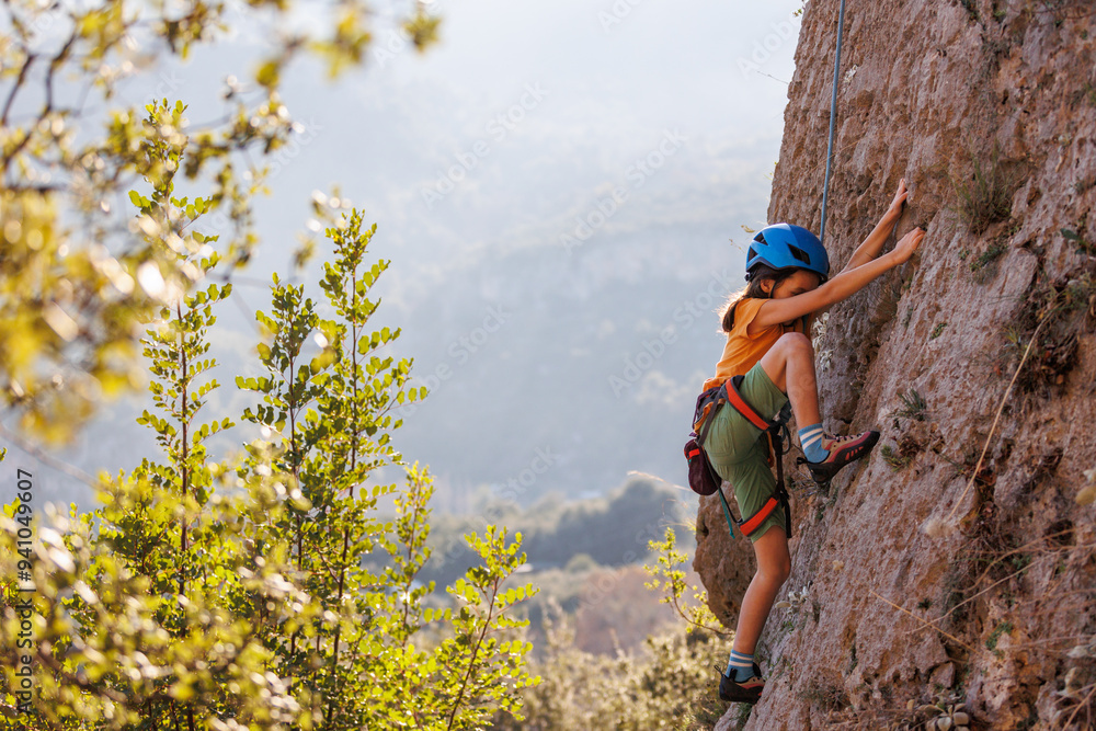 Obraz premium rock climber boy. child trains rock climbing at summer camp. sport in nature. rock climbing. on the rocks.