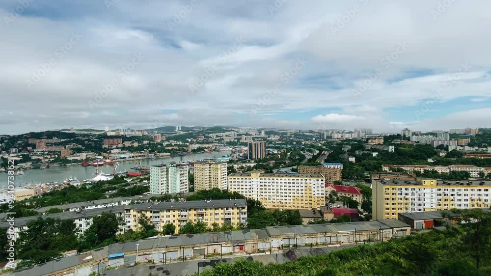 There is a view of the city by the sea from a high hill. A large number of buildings and a seaport are visible There is a view of the city by the sea from a high hill. A large number of buildings and a seaport are visible