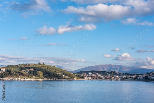 Old tourist town on Corfu island, Greece. Fishing village on seashore with houses, bay with blue water and mountains