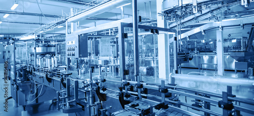 Modern automated factory assembly line for bottling beverages. Advanced industrial equipment and machinery emphasize efficiency, automation, and high-tech manufacturing processes in sterile