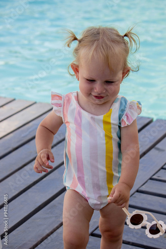 little girl on the background of the pool in a beautiful swimsuit and sunglasses. rest.