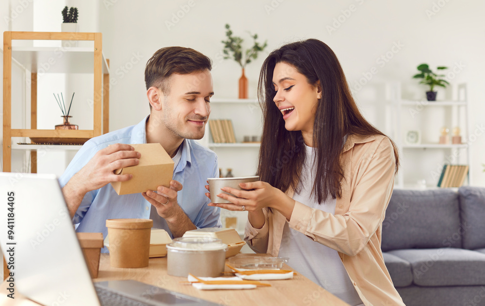 Happy married couple sits at a table in their home, eating a takeaway meal or delivery food. Their lunch is filled with joy and contentment, highlighting the happiness of dining together. Happy married couple sits at a table in their home, eating a takeaway meal or delivery food. Their lunch is filled with joy and contentment, highlighting the happiness of dining together.