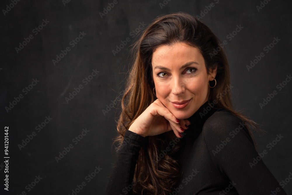 Close-up studio portrait of an attractive woman smiling against isolated dark background Close-up studio portrait of an attractive woman smiling against isolated dark background