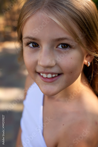 a young girl wearing a white dress with a white sash around her neck.