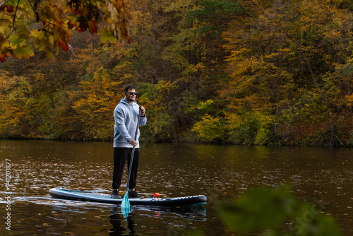 Man Paddleboarding in Autumn Lake photo