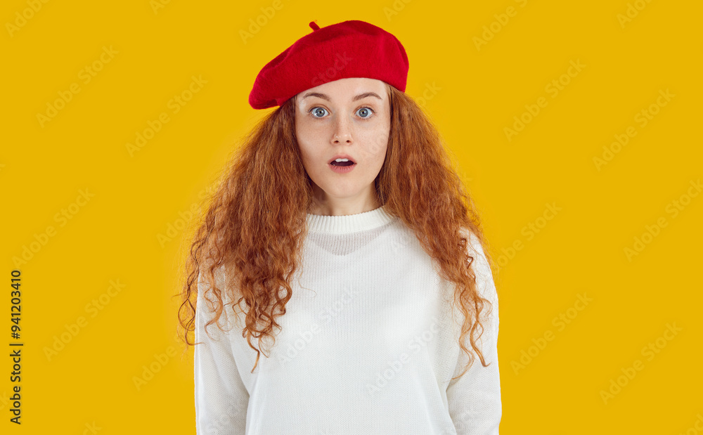 Portrait of beautiful, young woman in sweatshirt and red beret, looking into the camera with surprised expression on her face. Studio photo of lovely girl with long, wavy hair on isolated background. Portrait of beautiful, young woman in sweatshirt and red beret, looking into the camera with surprised expression on her face. Studio photo of lovely girl with long, wavy hair on isolated background.