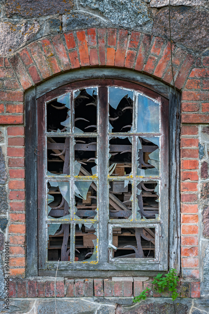 Old arched window with broken glass. Window of a ruined barn facade ...