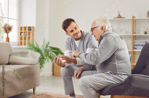 Foto Senior nursing, health care of elderly people, young male geriatric nurse helping old man with phone