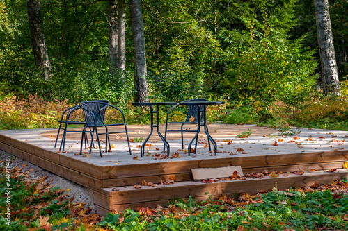 Close-up of a wooden rectangular platform, oblique angular view, in a suburban garden, green grass with with dry leaves. photo