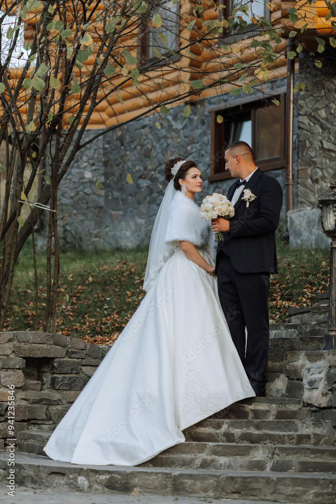 A bride and groom stand on a set of stairs, the bride wearing a white dress A bride and groom stand on a set of stairs, the bride wearing a white dress