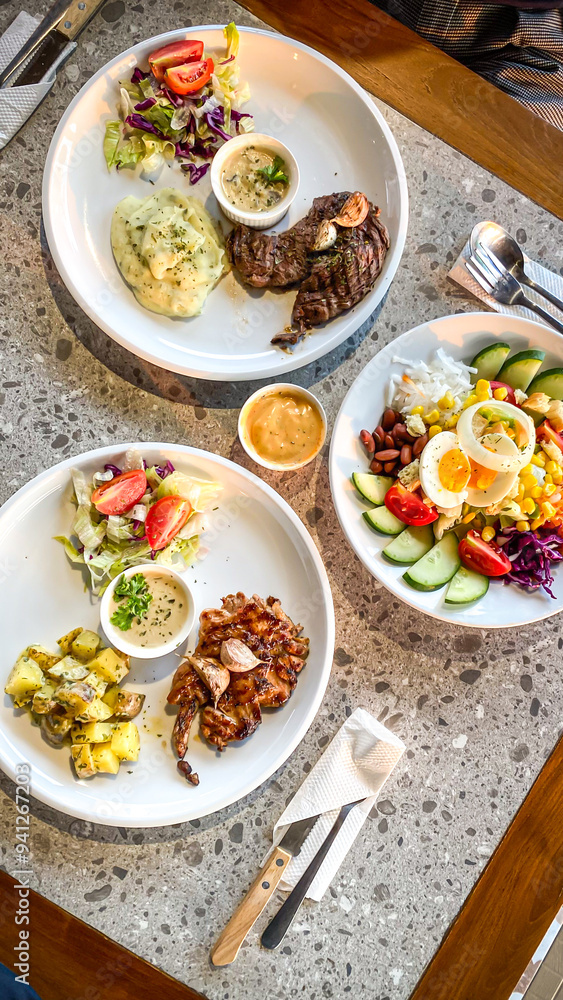 Flat lay photo of beef and chicken steak with garnished fresh vegetable salad and mashed potatoes at a western cuisine restaurant. Flat lay photo of beef and chicken steak with garnished fresh vegetable salad and mashed potatoes at a western cuisine restaurant.