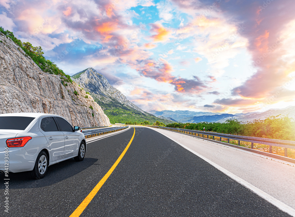 The car is driving along the highway surrounded by picturesque nature.