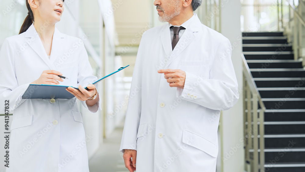 Fototapeta premium Man and woman in white coats consulting while walking in lobby