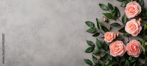 Soft pink roses and lush green leaves create serene and elegant floral arrangement on textured gray background, evoking feelings of tranquility and beauty.