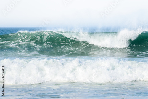 Pacific ocean waves breaking on the shore sending up plumes of spray on a windy autumn day photo