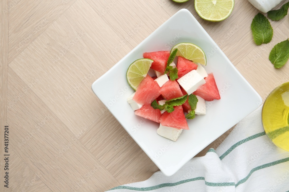 Tasty salad with watermelon, feta cheese, lime and mint on wooden table, flat lay. Space for text Tasty salad with watermelon, feta cheese, lime and mint on wooden table, flat lay. Space for text