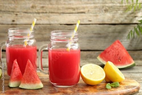 Tasty watermelon drink in mason jars and fresh fruits on wooden table, closeup