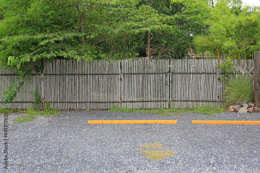 Empty parking spaces in public park with bumps barrier against bamboo wooden fence. Empty parking spaces in public park with bumps barrier against bamboo wooden fence.