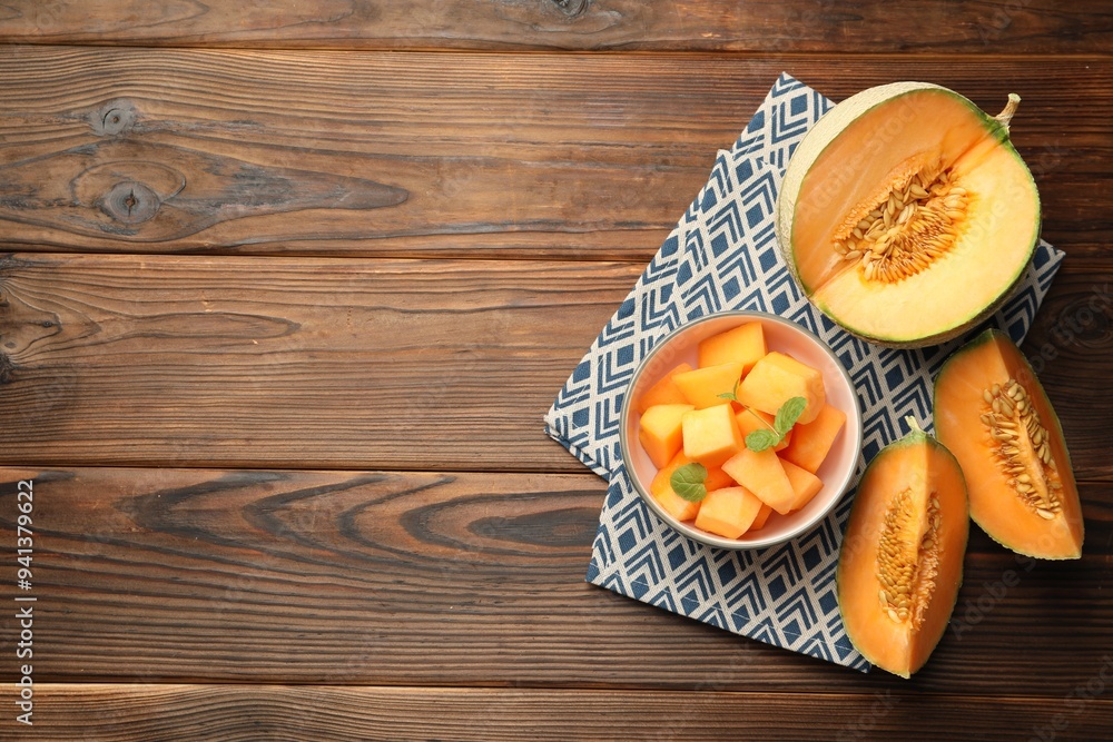 Pieces of Cantaloupe melon and mint in bowl on wooden table, flat lay. Space for text Pieces of Cantaloupe melon and mint in bowl on wooden table, flat lay. Space for text