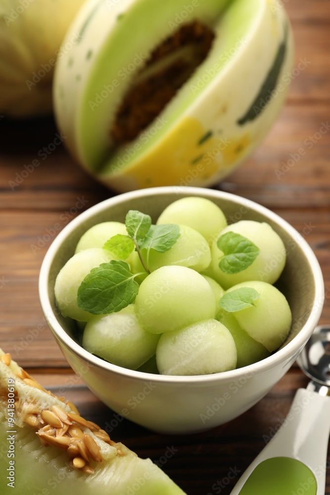 Melon balls in bowl and fresh fruit on wooden table, closeup Melon balls in bowl and fresh fruit on wooden table, closeup