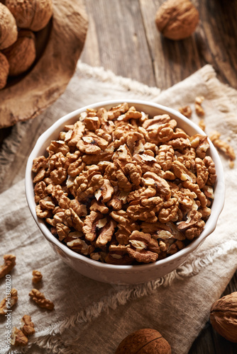 Shelled walnuts in a bowl with whole nuts