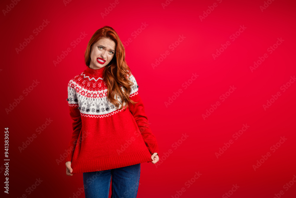 Photo of young upset lady showing her worst present seasonal sweater for happy new year holiday isolated on red color background Photo of young upset lady showing her worst present seasonal sweater for happy new year holiday isolated on red color background