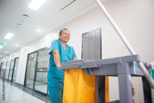Wallpaper Mural A floor mop in a blue uniform pushes a cart loaded with cleaning supplies and new epoxy floor protection kits into an empty hospital warehouse. Torontodigital.ca